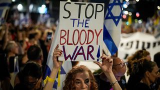 إسرائيلية تتحمل لافتة كتب عليها أوقفوا الحرب الدموية في مظاهرة لأهالي الأسرى والرهائن في تل أبيب