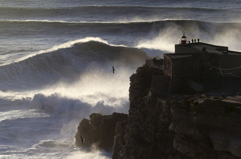 People on the top of the Nazare lighthouse watch as waves break during a big wave surfing session at the Praia do Norte, or North beach, in Nazare, February 2017
