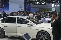 Visitors look at cars at the BYD booth during the China Auto Show in Beijing, China in April