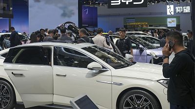 Visitors look at cars at the BYD booth during the China Auto Show in Beijing, China in April
