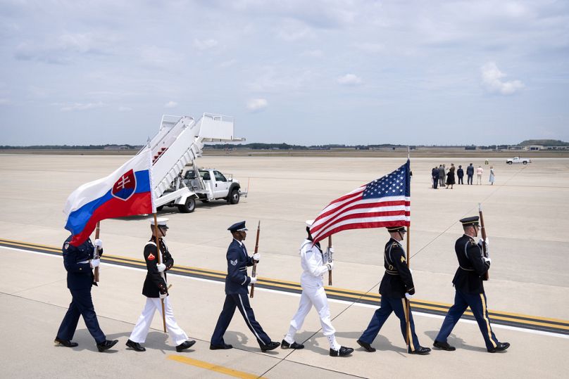 An honor guard carries US and Slovakian flags as they march across the tarmac before the arrival of Slovakia's President Peter Pellegrini, 8 July 2024