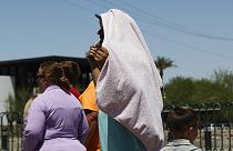 شخص يستخدم بطانية لحجب الشمس أثناء انتظاره لالتقاط صورة عند لافتة "مرحبًا بكم في لاس فيغاس" يوم الاثنين 8 يوليو 2024 