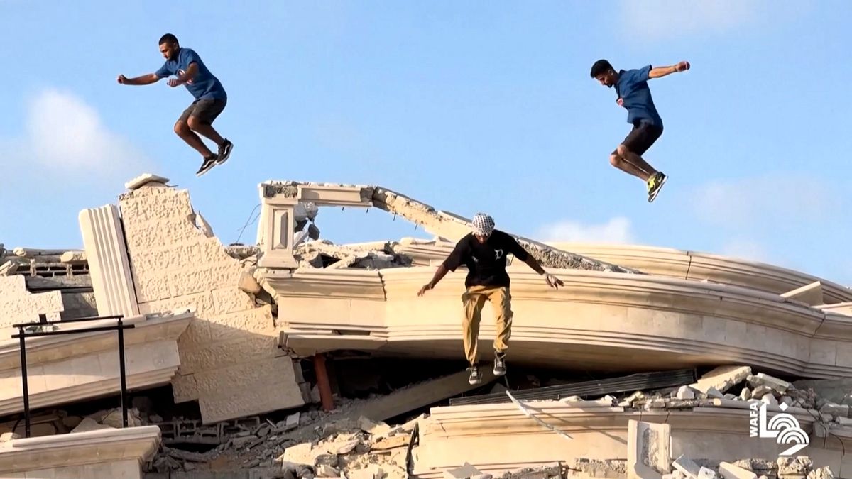 Des jeunes s'entraînent au parkour au dessus d'un immeuble détruit.