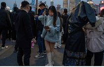 A woman looks at her phone on a selfie stick on the bund, a historic riverside district of Shanghai known for its Western architecture on March 18, 2024.