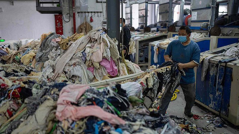 A worker feeds discarded textiles to a shredding machine at the Wenzhou Tiancheng Textile Company, one of China's largest cotton recycling plants in Wenzhou in eastern China