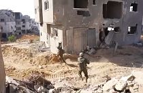 Soldados a caminhar num bairro destruído da Faixa de Gaza
