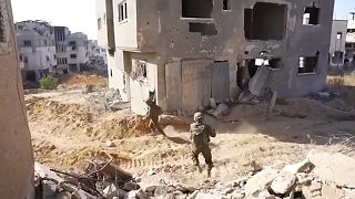 Soldados a caminhar num bairro destruído da Faixa de Gaza