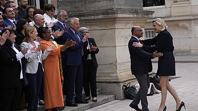 French far-right leader Marine Le Pen, right, arrives to pose with newly elected parliament members of the National Rally party at the National Assembly Wednesday, July 10, 20