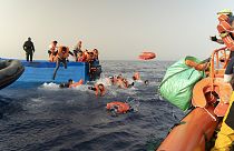 Les volontaires de SOS Méditerranée, à droite, aident à transférer les passagers d'un bateau de migrants sur leur propre navire de sauvetage, le mardi 9 juillet 2024. 