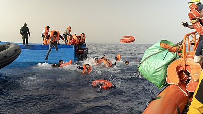 Rescue personnel of the SOS Mediterranee's volunteers, right, help transfer the passengers from a wooden migrant boat onto their own rescue vessel, on Tuesday, July 9, 2024. 