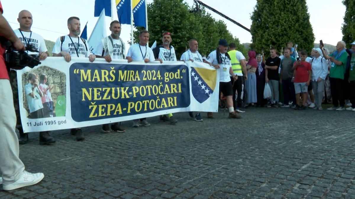 Menschen halten einen Banner bei dem Friedensmarsch in Srebrenica.