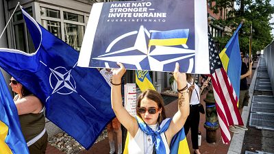 Ukrainian refugee Mariia Hlyten holds a sign outside the NATO summit in Washington.