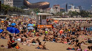 Des personnes prennent un bain de soleil sur la plage de Barcelone, en Espagne, le 9 juillet 2021. 