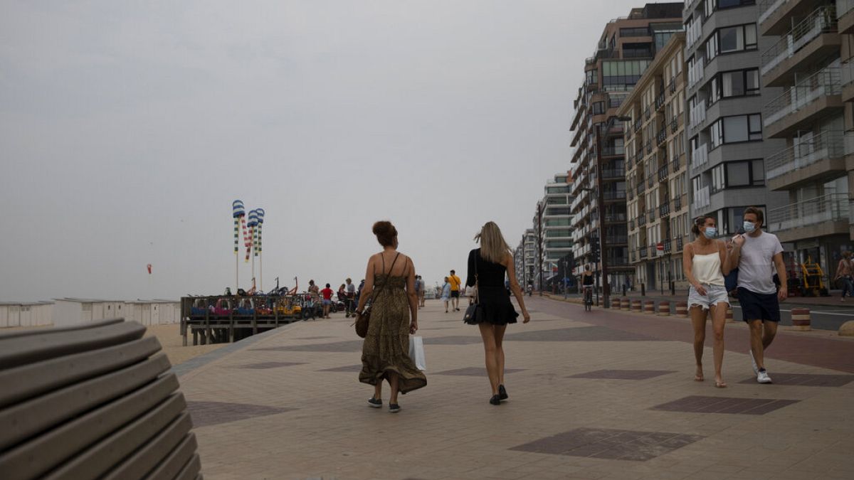 People walk on the promenade along the coastline at the Belgian seaside resort of Knokke, Belgium, Tuesday, Aug. 11, 2020. 