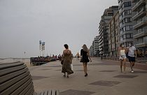 People walk on the promenade along the coastline at the Belgian seaside resort of Knokke, Belgium, Tuesday, Aug. 11, 2020. 