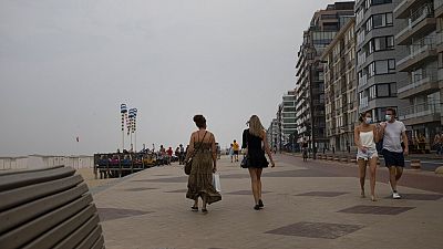 Люди идут по набережной вдоль береговой линии на бельгийском морском курорте Кнокке, Бельгия, вторник, 11 августа 2020 года. 