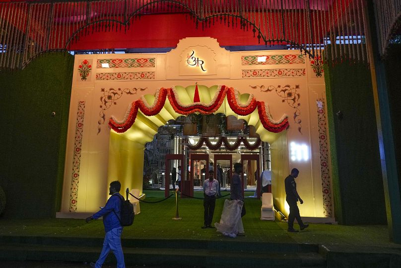 People walk past the venue decorated with lights ahead of billionaire Mukesh Ambani's son Anant Ambani's wedding to Radhika Merchant at Jio World Convention Centre in Mumbai