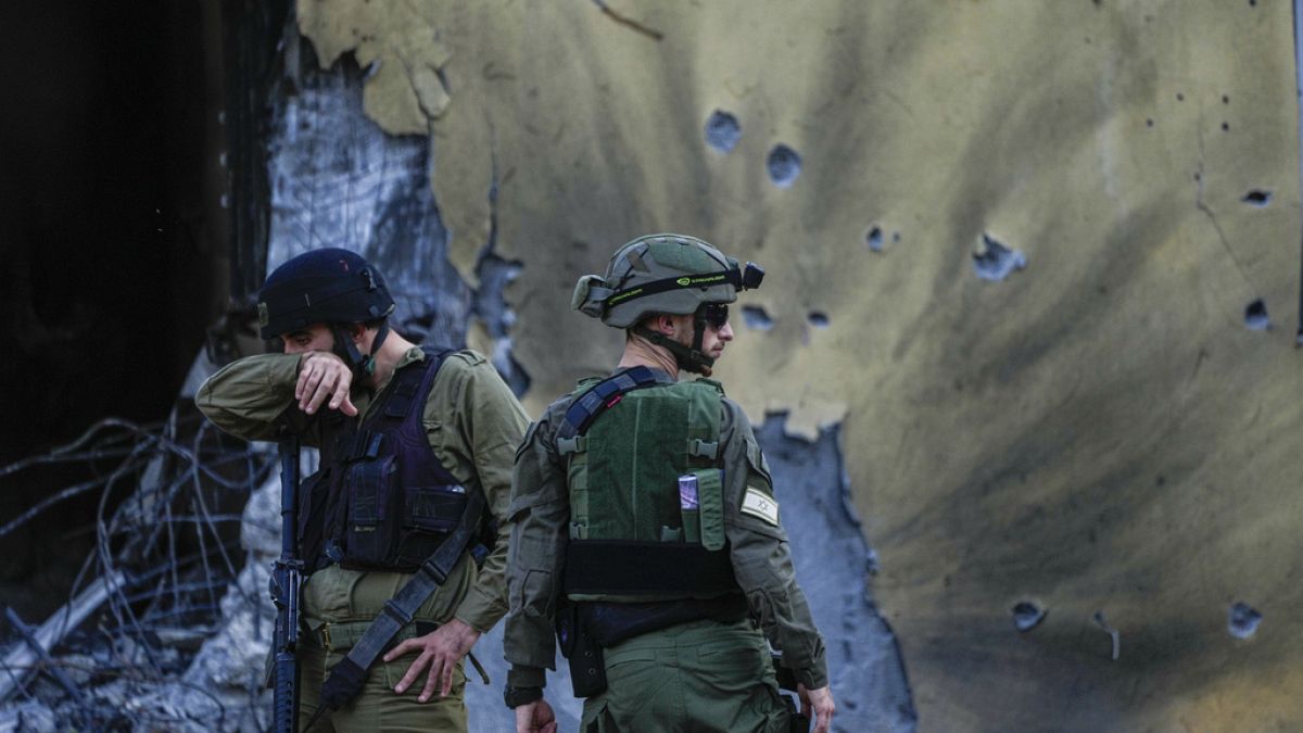 Israeli soldiers walk past houses destroyed by Hamas militants in Kibbutz Be'eri, Israel, Saturday, Oct. 14, 2023. 