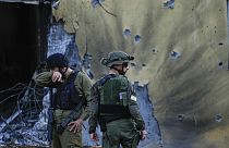 Israeli soldiers walk past houses destroyed by Hamas militants in Kibbutz Be'eri, Israel, Saturday, Oct. 14, 2023. 