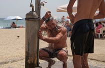 A man takes a shower during a heatwave at a beach in Faliro seaside district of Athens, on 13 June 2024. 