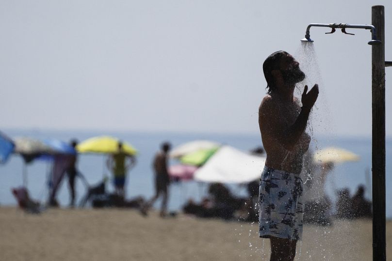 FILE - A man takes a shower on a beach on a hot day in Ostia, 23 August 2023