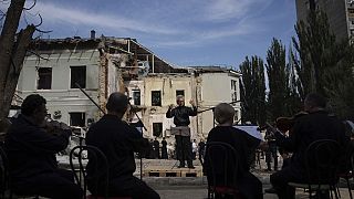 El director German Makarenko dirige la orquesta, que toca en el lugar del ataque con misiles rusos al hospital infantil, en Kiev, Ucrania, el 12 de julio de 2024.