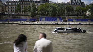 Pessoas sentadas ao longo do rio Sena com bancadas instaladas nas suas margens, 4 de julho 2024