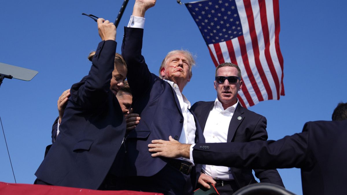 Republican presidential candidate former President Donald Trump gestures as he is surrounded by U.S. Secret Service agents as he leaves the stage at a campaign rally