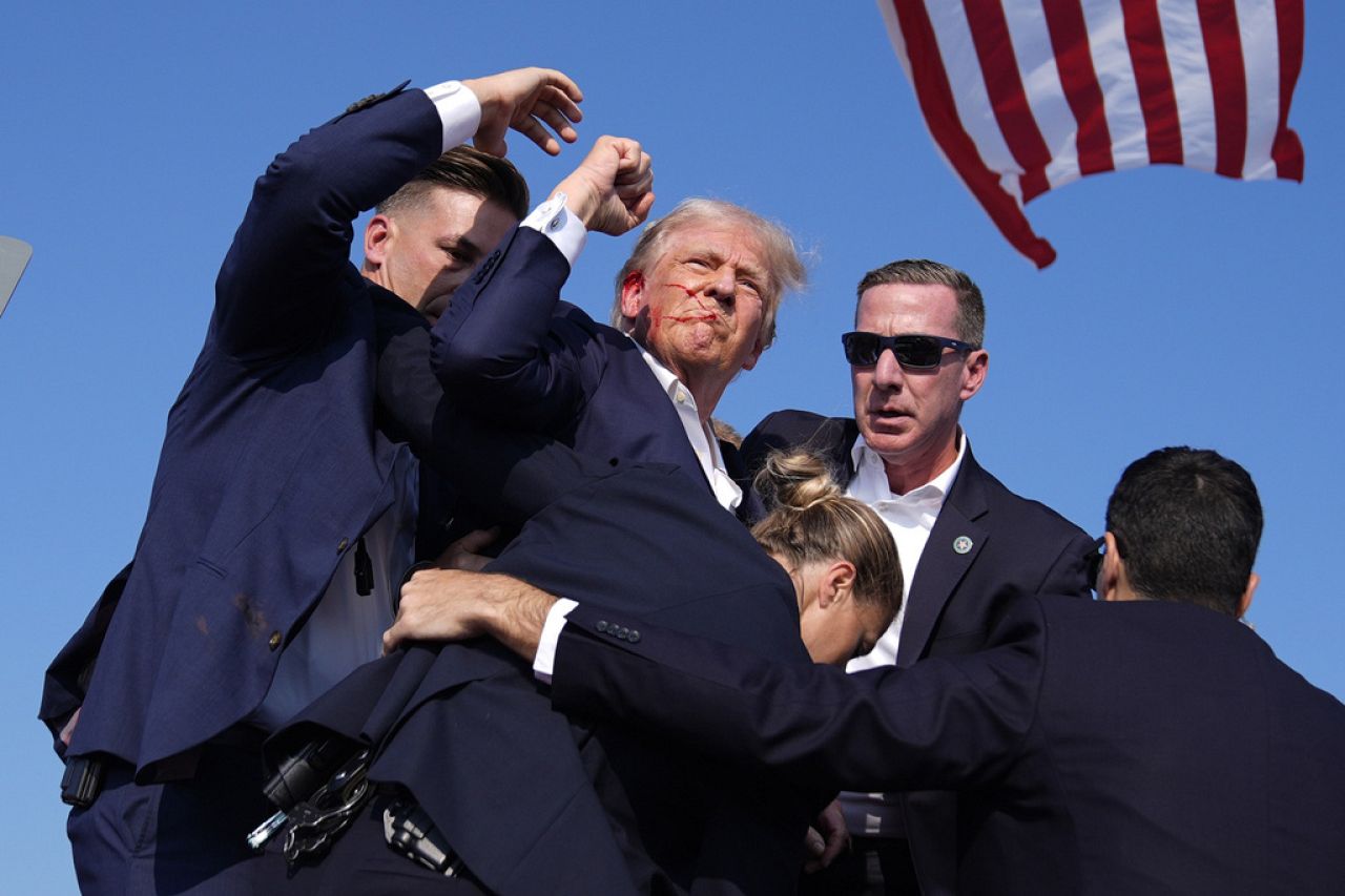 Donald Trump gestures as he is surrounded by Secret Service agents after a shooting at his campaign rally in Butler