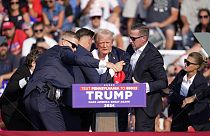 Бывшему кандидату в президенты США от Республиканской партии Дональду Трампу помогают сойти со сцены во время предвыборного мероприятия в Батлере, штат Пенсильвания, в субботу,