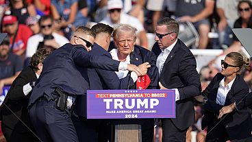 El candidato presidencial republicano, el expresidente Donald Trump, es ayudado a bajar del escenario en un acto de campaña en Butler, Pensilvania, el sábado,