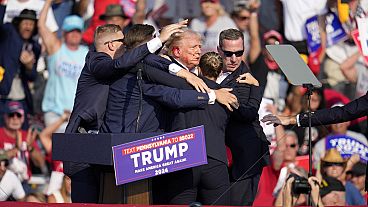 Donald Trump wird bei einer Wahlkampfveranstaltung in Butler, Pennsylvania, am Samstag, 13. Juli 2024, von der Bühne geholfen. 