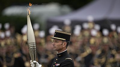 Col. Thibault Vallette, of the Cadre Noir de Saumur, carries the Olympic torch during the Bastille Day parade Sunday, July 14, 2024 in Paris.