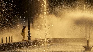 Ein städtischer Angestellter kühlt sich am Donnerstag, 11. Juli 2024 neben einem Stadtbrunnen in Bukarest ab.
