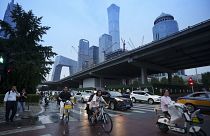 Peatones cruzan una intersección con el fondo del distrito central de negocios en Pekín, 12 de julio de 2024. 