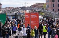 Vigilantes comprueban el acceso de los turistas al código QR en el exterior de la principal estación de tren de Venecia, Italia, jueves 25 de abril de 2024.