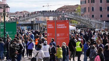 Vigilantes comprueban el acceso de los turistas al código QR en el exterior de la principal estación de tren de Venecia, Italia, jueves 25 de abril de 2024.