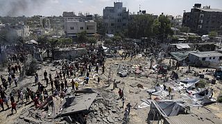 فلسطينيون يتفقدون الأضرار التي لحقت بموقع تعرض للقصف الإسرائيلي على خان يونس جنوب قطاع غزة، السبت، 13 يوليو 2024.