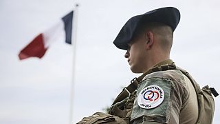 A soldier stands by the French flag at the military camp set up in the Vincennes woods in Paris on Monday