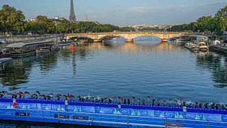 Спортсмены ныряют в реку Сена с моста Александра III во время первого этапа тестовых соревнований по триатлону среди женщин на Олимпийских играх 2024 года в Париже, 17 августа 2023 года.