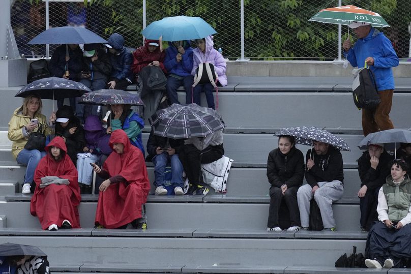 Varias personas se cubren de la lluvia durante el torneo de tenis Abierto de Francia en el estadio Roland Garros de París, el miércoles 29 de mayo de 2024. 