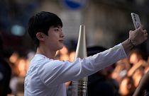 Jin, the oldest member of K-pop supergroup BTS, males a selfie with the Olympic torch, Sunday, July 14, 2024 in Paris.