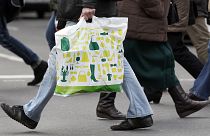 Ein Mann mit einer Einkaufstasche überquert eine Straße in Berlin, Deutschland