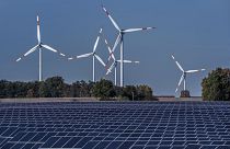 Wind turbines turn behind a solar farm in Rapshagen, Germany