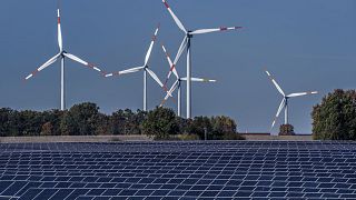 Rüzgar türbinleri Rapshagen, Almanya'daki bir güneş enerjisi çiftliğinin arkasında dönüyor