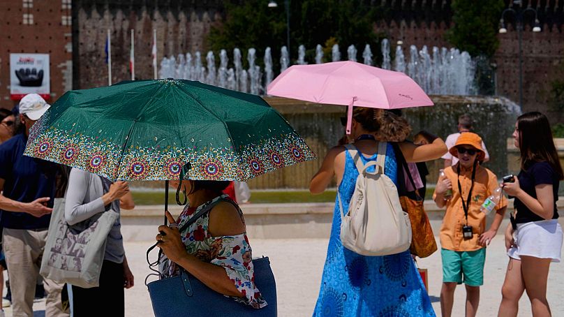 Tourists shelter from the sun in front of the Sforzesco Castle in Milan, Italy, 16 July 2024.