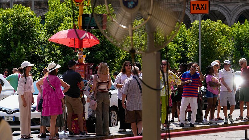 Tourists wait for a bus under the sun in Milan, Italy, Tuesday, 16 July 2024.