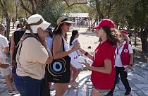 Εθελόντρια του Ερυθρού Σταυρού προσφέρει νερό σε τουρίστες