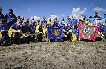 Ukrainian prisoners of war hold flags of their units as they pose for a photo after a prisoners exchange at an undisclosed location in Ukraine.