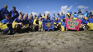Ukrainian prisoners of war hold flags of their units as they pose for a photo after a prisoners exchange at an undisclosed location in Ukraine.